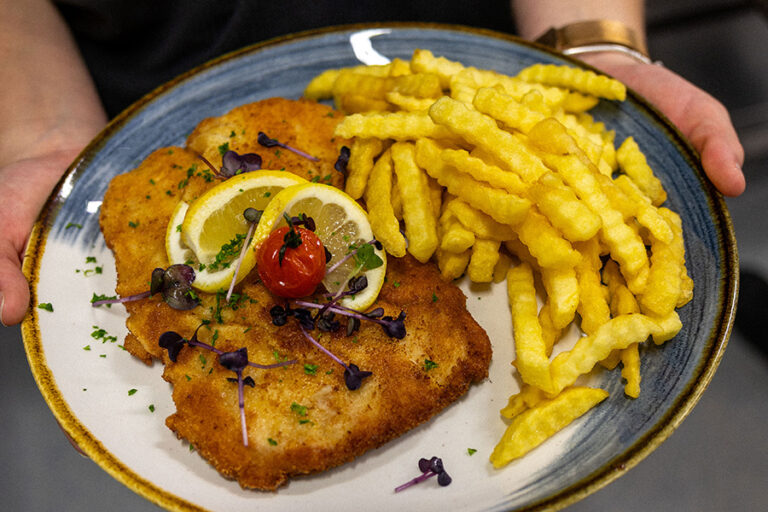 Knuspriges Schnitzel mit Zitronenscheiben und Pommes, traditionell zubereitet im Gasthof Reblitz in Nedensdorf.